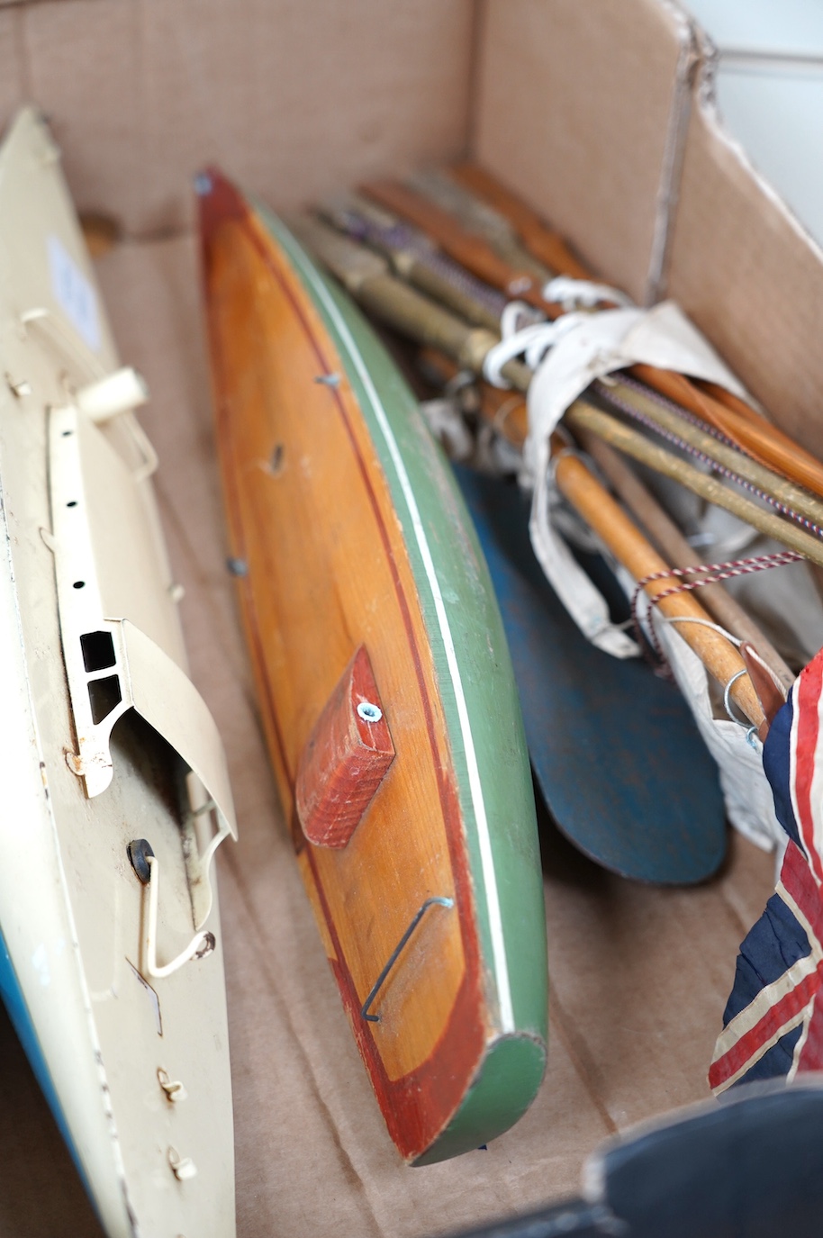 Two Tri-ang pond yachts, one painted tin plate, the other painted wood, together with various masts and flags. Condition - poor to fair